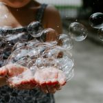 Kind haelt behutsam eine grosse Seifenblase und erlebt achtsames Staunen