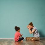 Kinderyoga Achtsamkeitsuebung mit Erwachsener und Kind im Sitzen im ruhigen Raum