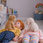 Kinderyoga Ruheuebung mit zwei Kindern im Liegen und Kuscheltieren im Kinderzimmer